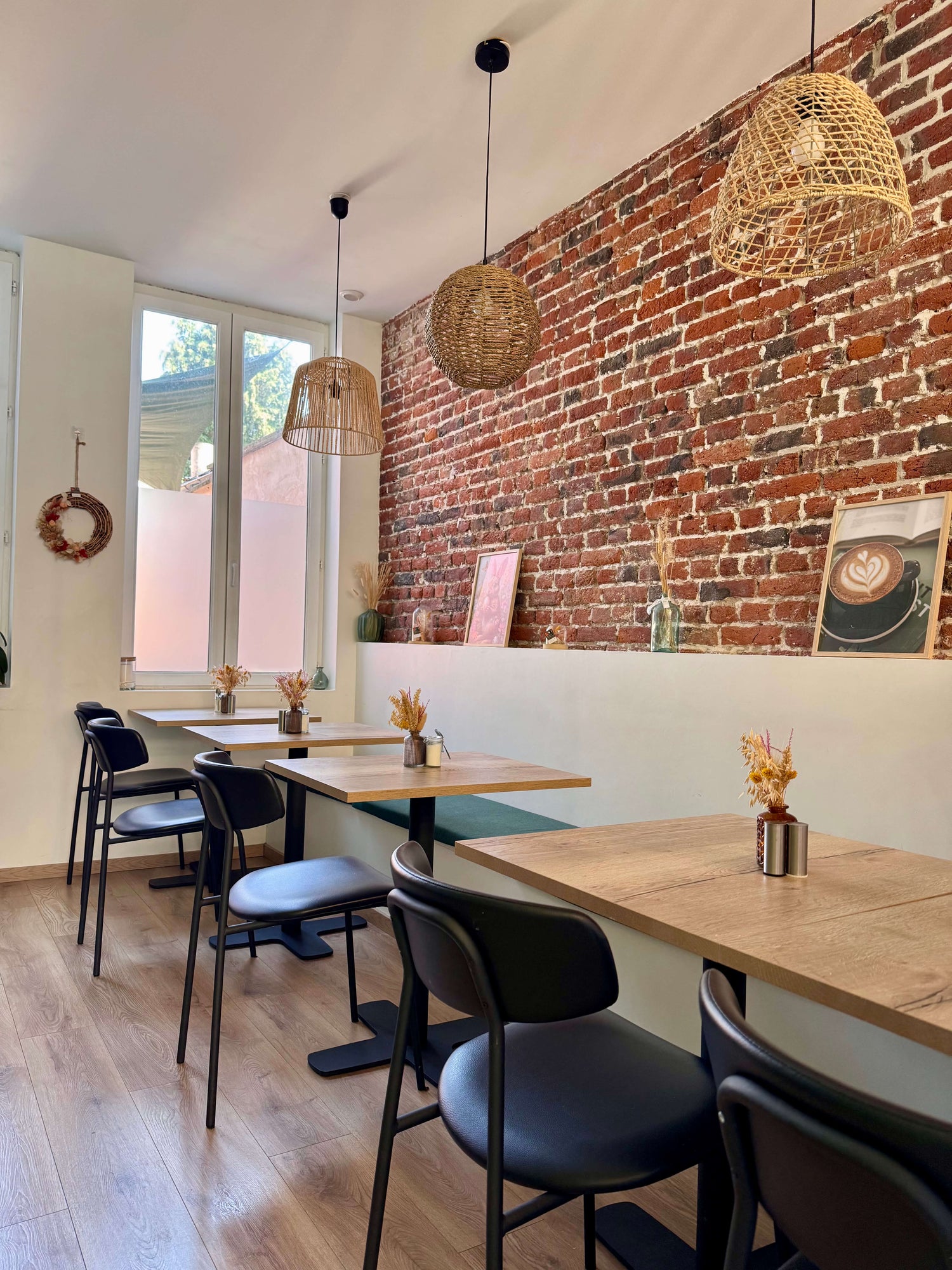Photo de l'intérieur cosy et chaleureux du salon de thé : table en bois, mur en brique